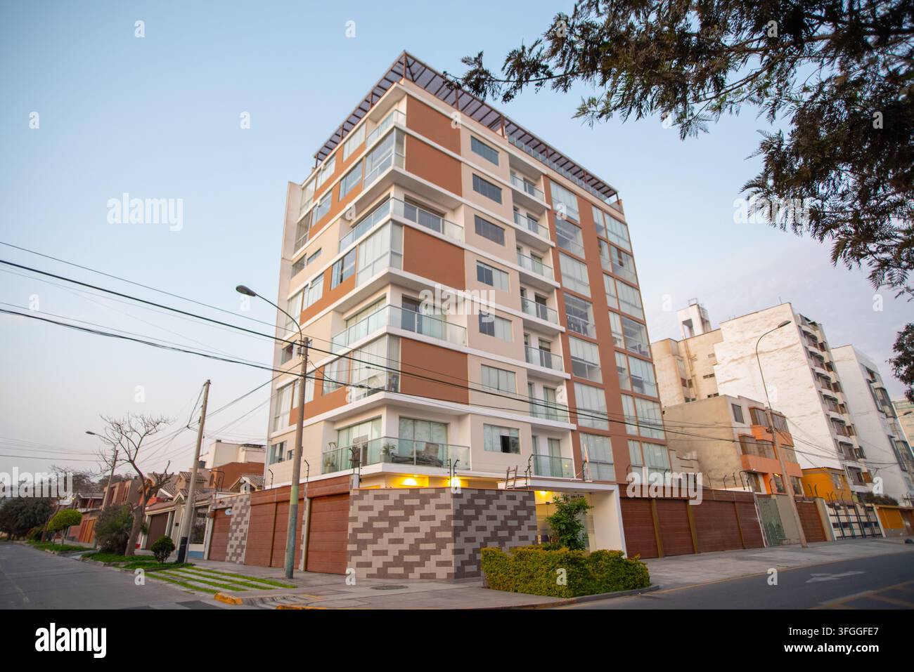 Moderne Wohnhausfassade: Ein zeitgenössisches Wohnhaus erhebt sich hoch an einer Stadtstraße und weist eine schlanke Fassade mit einer Mischung aus Glas auf Stockfoto
