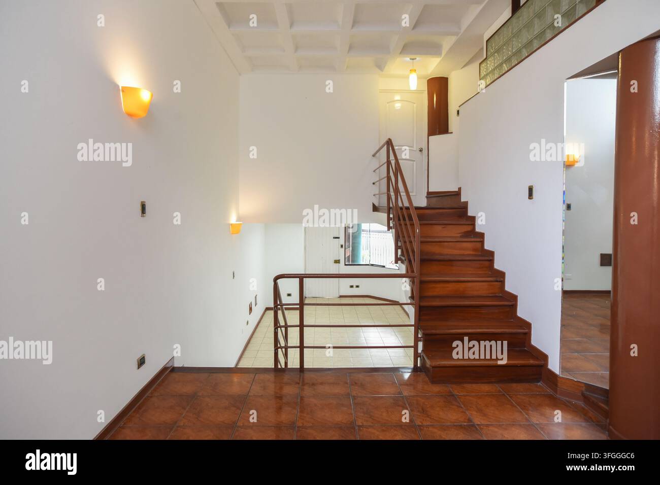 Moderne Innenarchitektur mit Treppe: Ein geräumiges und helles Interieur zeigt ein zeitgenössisches Design mit einer Holztreppe, die zur oberen Etage führt Stockfoto