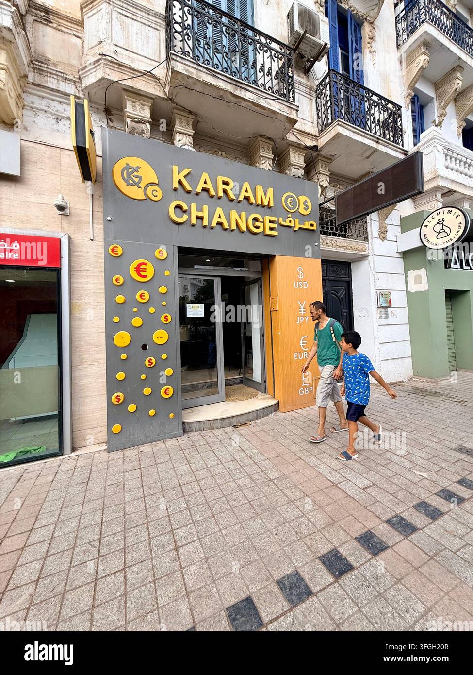 Fußgänger vor einem Geldwechselbüro in Tunis, Tunesien, mit arabischer Beschriftung und US-Dollar- und Euro-Symbolen - Smartphone-aufgenommenes Stockfoto