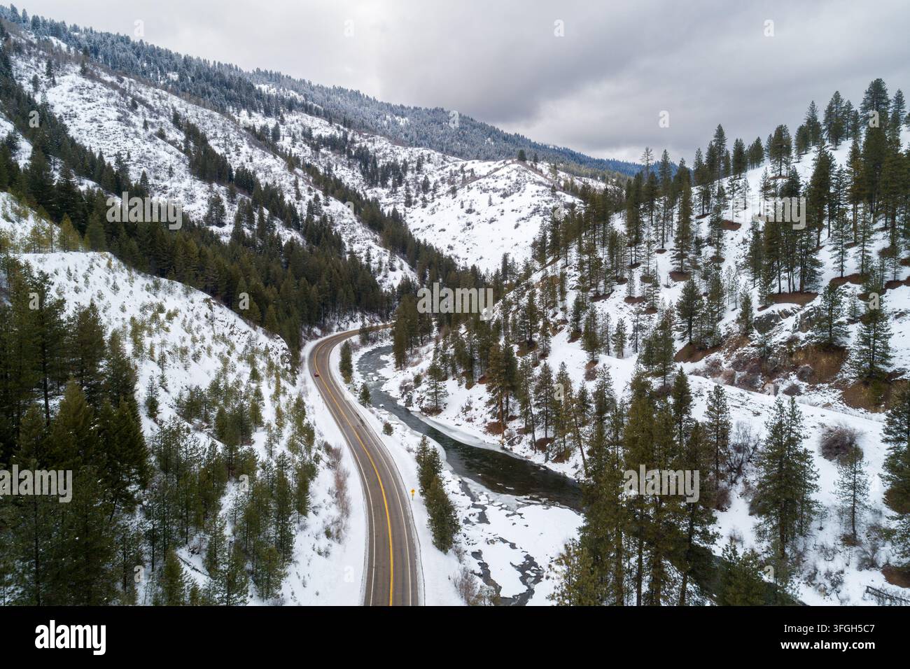 Winterstraße schlängelt sich durch schneebedeckte Kiefernwälder Stockfoto