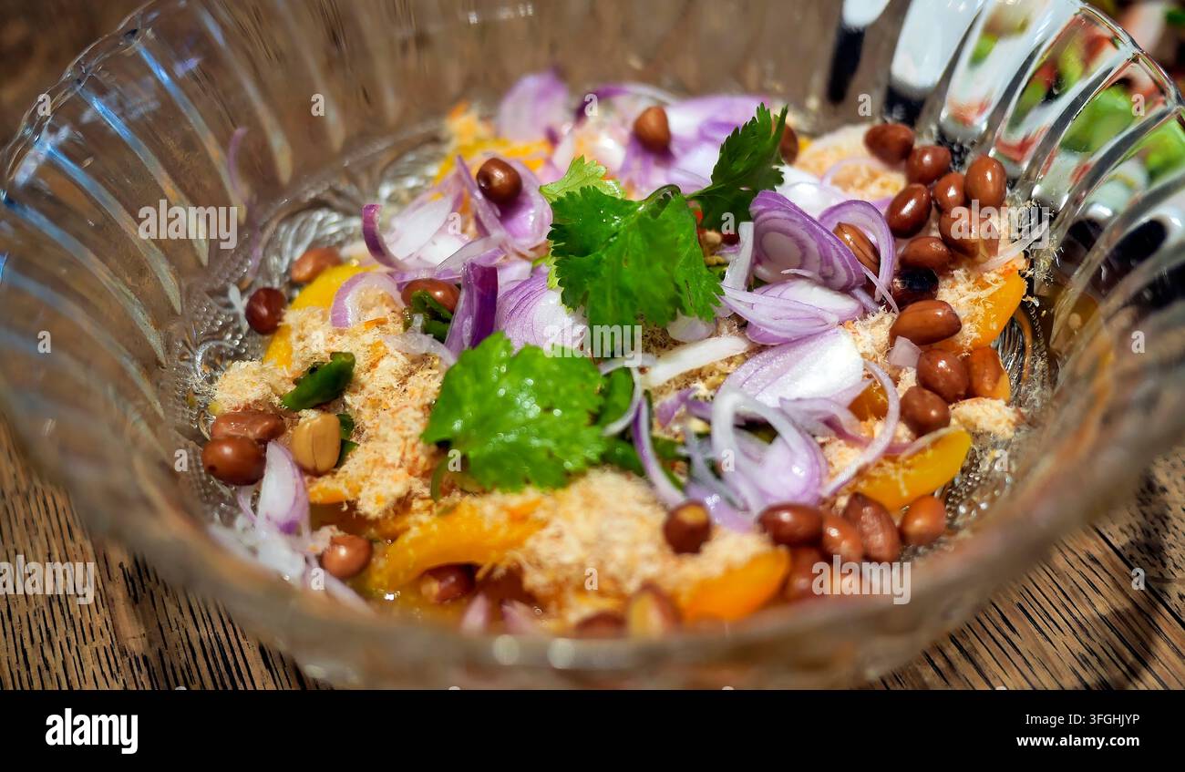 Ein köstlicher thailändischer Obstsalat Yum Mamuang Song Krueng. Stücke von saurem gelbem Mango oder Marianen-Pflaume werden mit einer scharfen Marinade, gerösteten Erdnüssen geworfen Stockfoto
