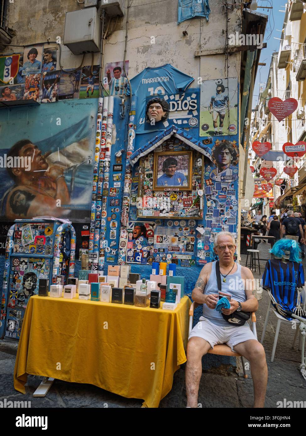 Verkäufer sitzt neben dem Parfümtisch und dem Maradona-Schrein, Neapel, Italien. Stockfoto