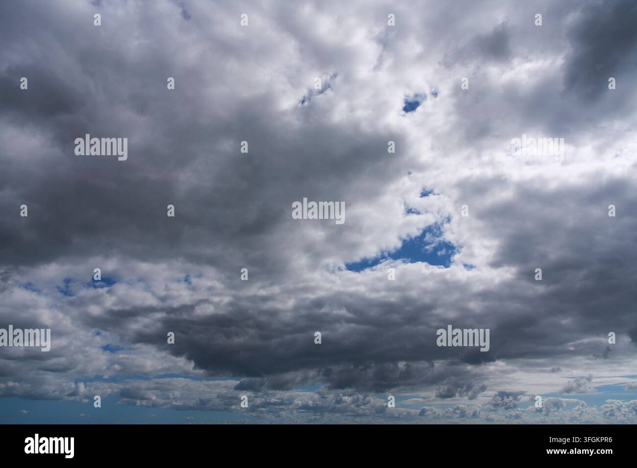 Weiße Wolken in blauem Himmel mit sanftem Licht über dem Horizont Stockfoto