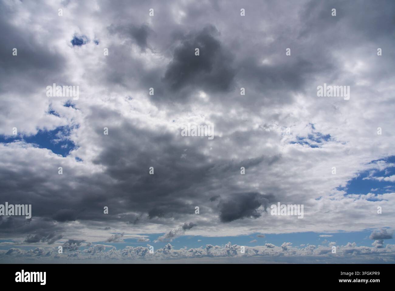 Weiße Wolken in blauem Himmel mit sanftem Licht über dem Horizont Stockfoto