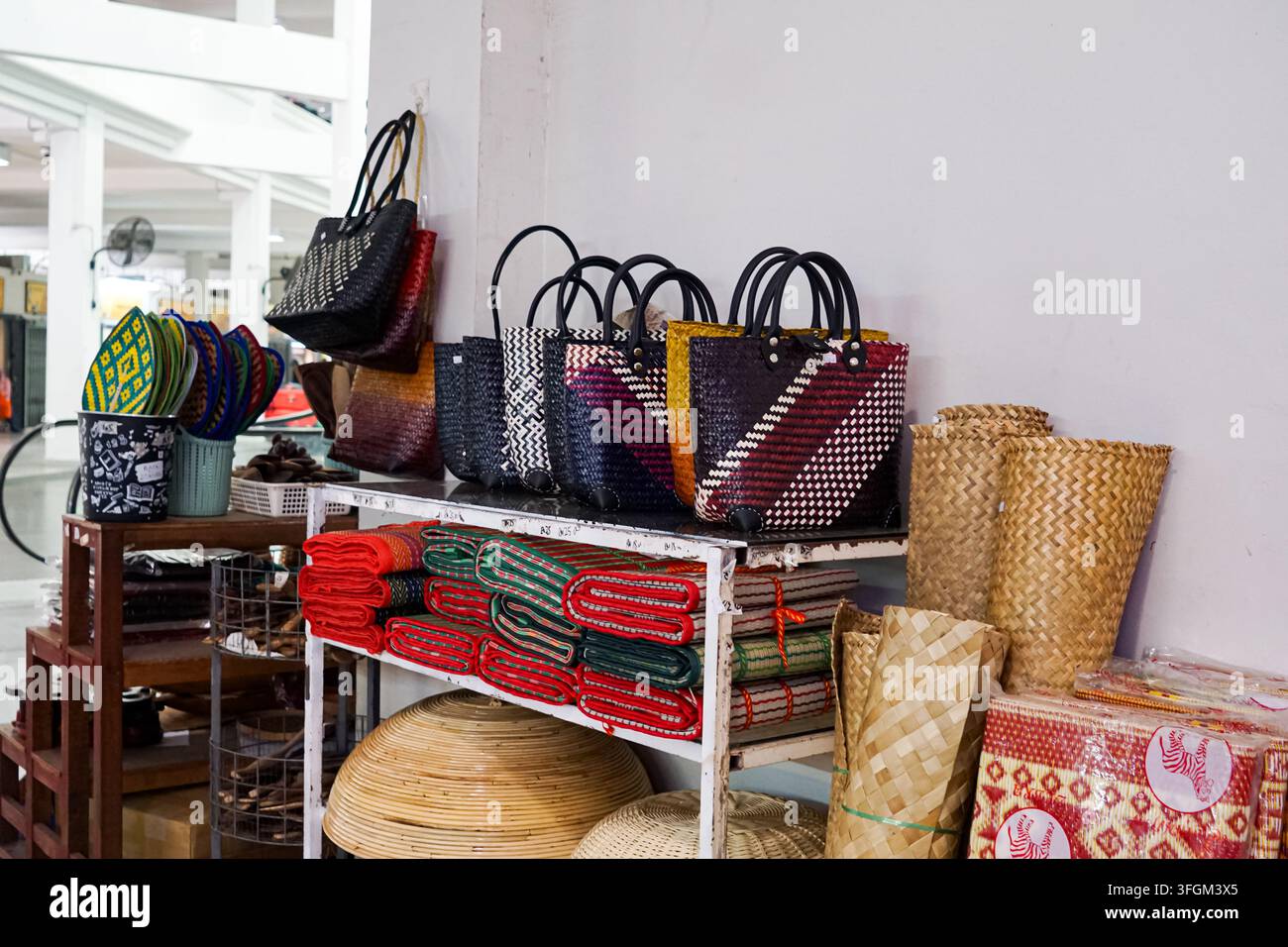 Eine Sammlung handgefertigter gewebter Taschen, Rattan-Körbe und gerollter Matten, ordentlich in Regalen bei Kedai Pasar Payang, Kuala Terengganu, Terengganu, präsentiert Stockfoto