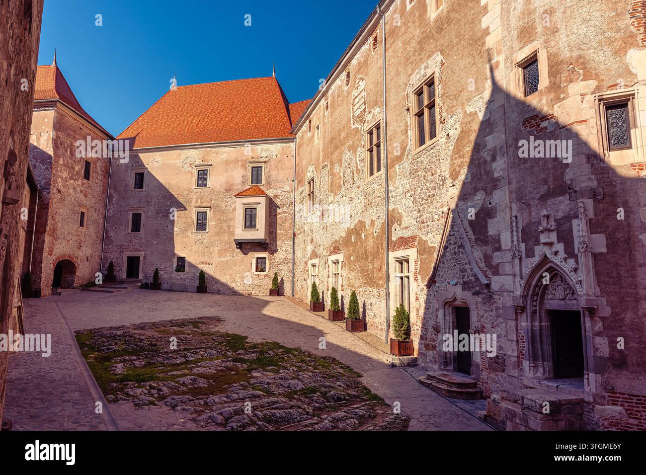 Sonnenbeschienene Innenhofmauer und gotische Türöffnung im Corvin-Schloss in Hunedoara, Rumänien Stockfoto