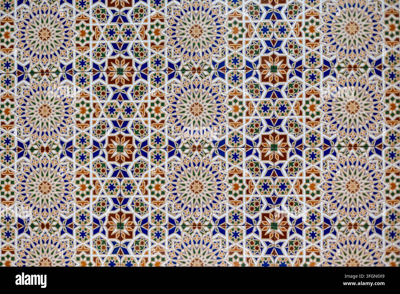 Verschnörkeltes geometrisches Keramikfliesenmuster in Blau und Grün. Bunte Keramikfliesen bilden ein kunstvolles sich wiederholendes geometrisches Muster mit floralen Rosetten in Stockfoto