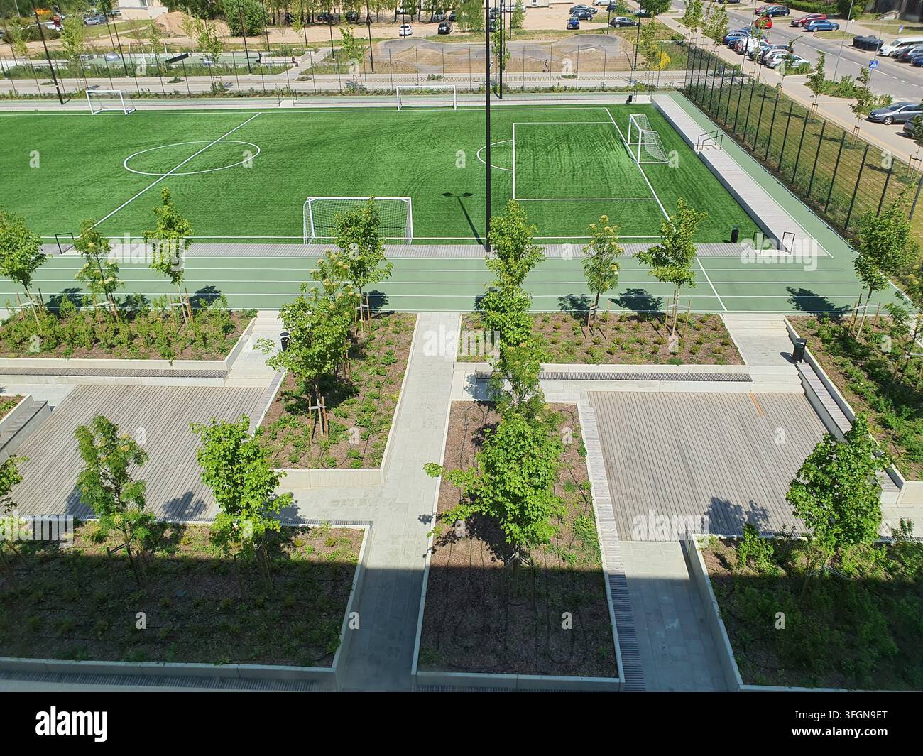 Luftaufnahme eines modernen Outdoor-Sportkomplexes mit zwei Kunstrasen-Fußballfeldern mit weißen Markierungen und Torpfosten, umgeben von Grün Stockfoto