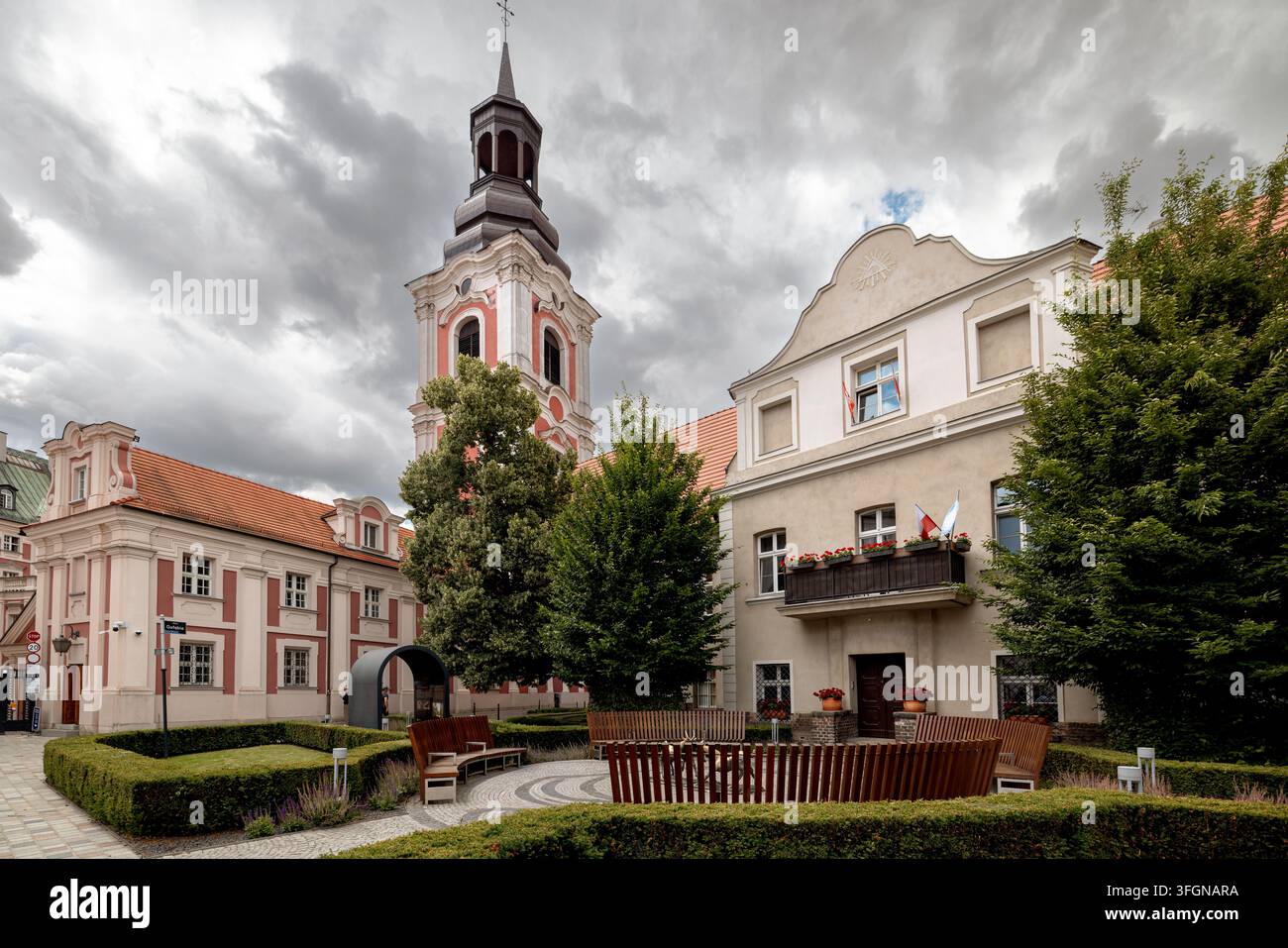 Ein gepflegter Hof neben dem ehemaligen Jesuitenkolleg rahmen seinen Barockturm, ausgewachsene Bäume und das benachbarte historische Wohnhaus. Stockfoto