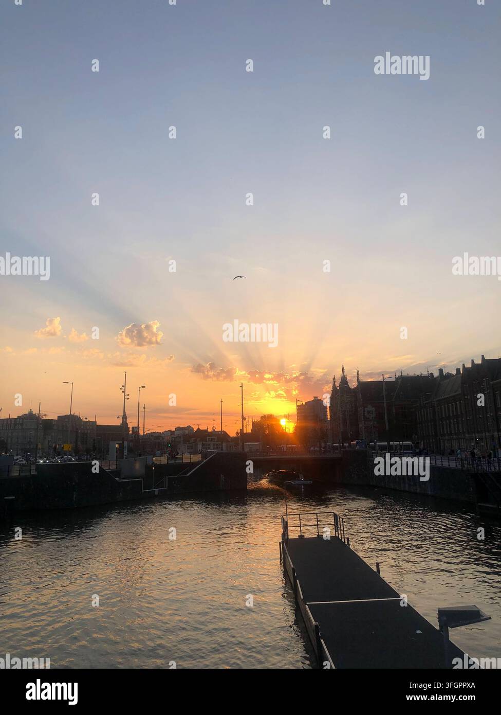 Sonnenstrahlen bei Sonnenuntergang über einem Stadtkanal, Amsterdam, Niederlande Stockfoto