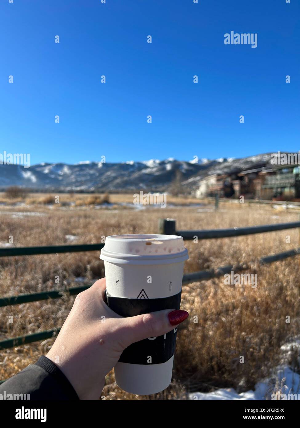 Frau hält Kaffee mit Winterbergblick, Park City, Utah Stockfoto