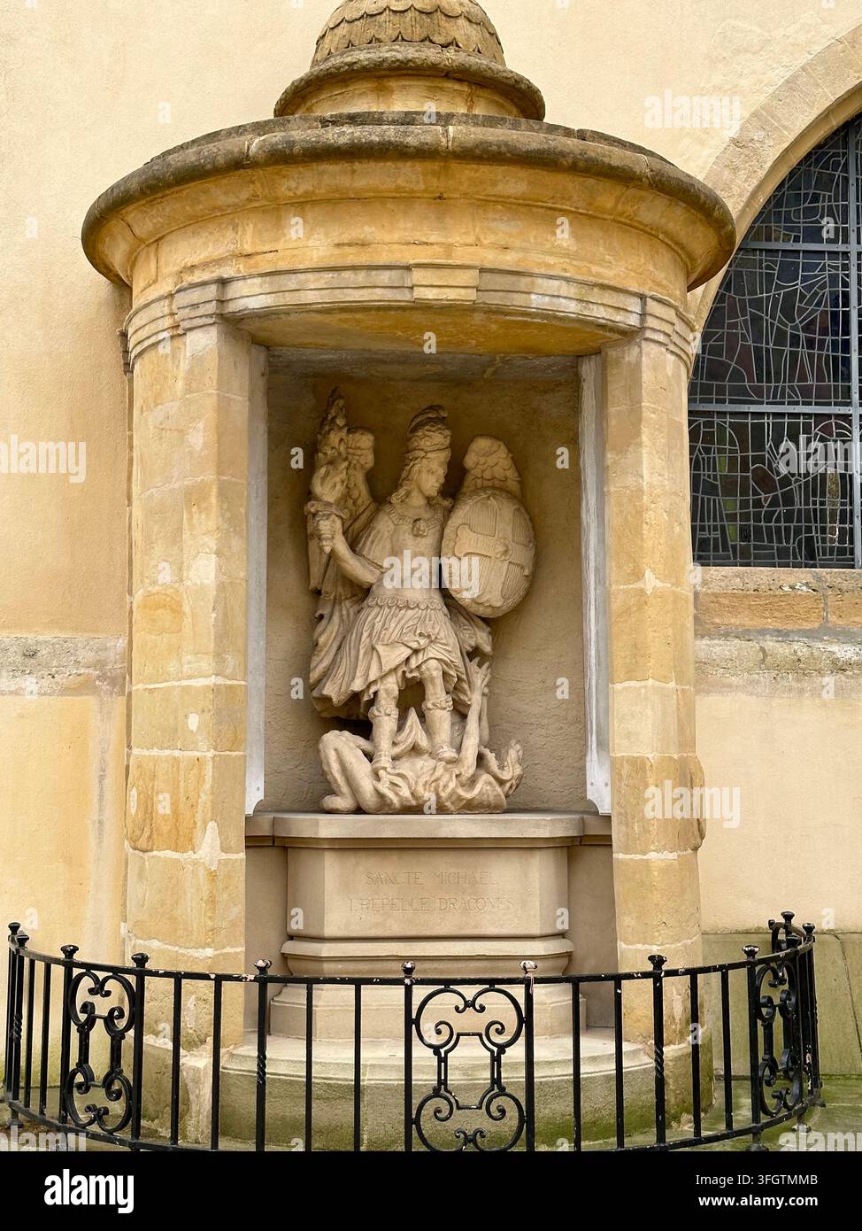 Steinskulptur des heiligen Michael, der einen Drachen erschlägt, in einer Nische. Detaillierte Stein-nische, die eine historische Skulptur des geflügelten heiligen Michael beherbergt. Stockfoto