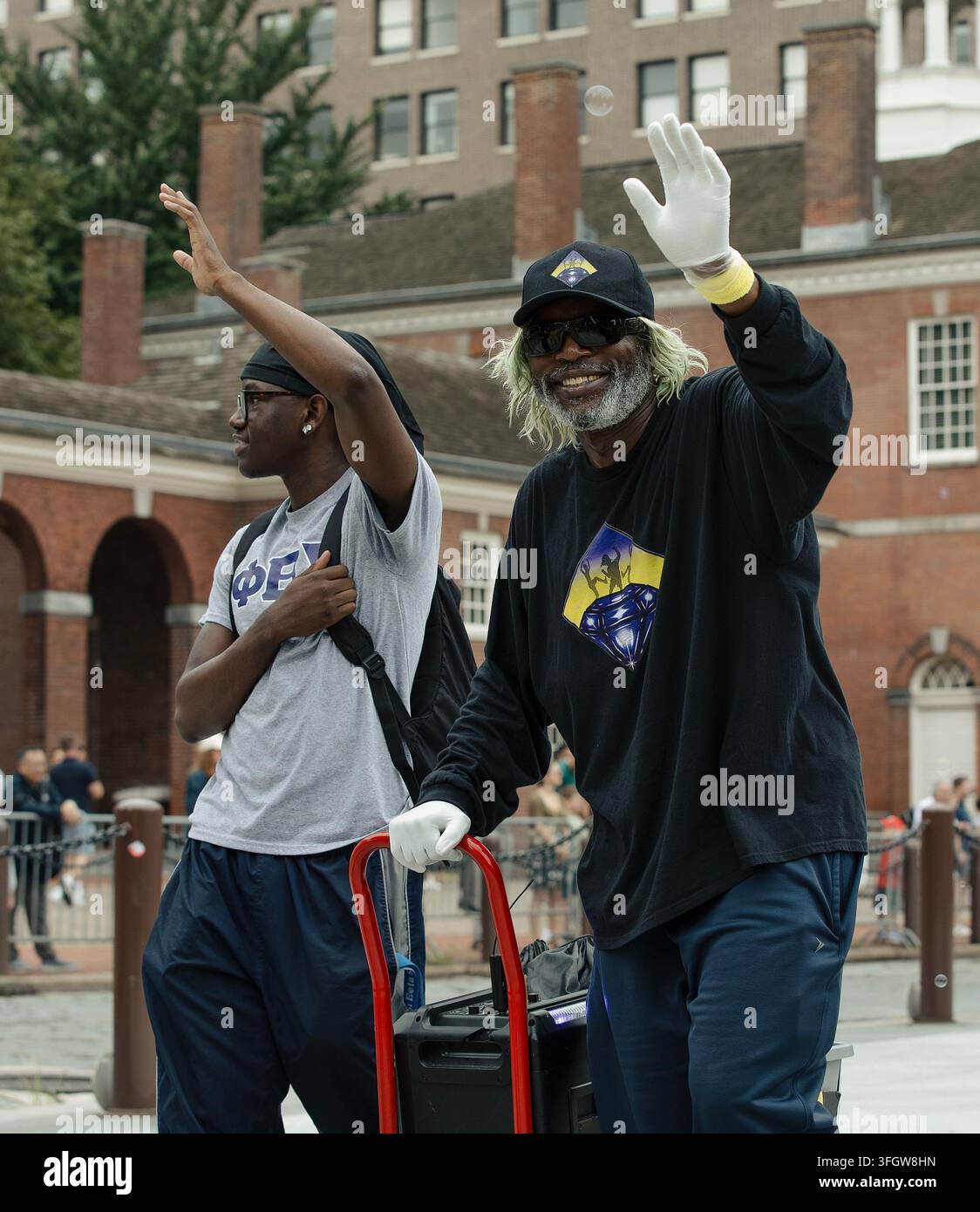 Zwei afroamerikanische Männer lächeln und winken auf einer Stadtstraße Stockfoto