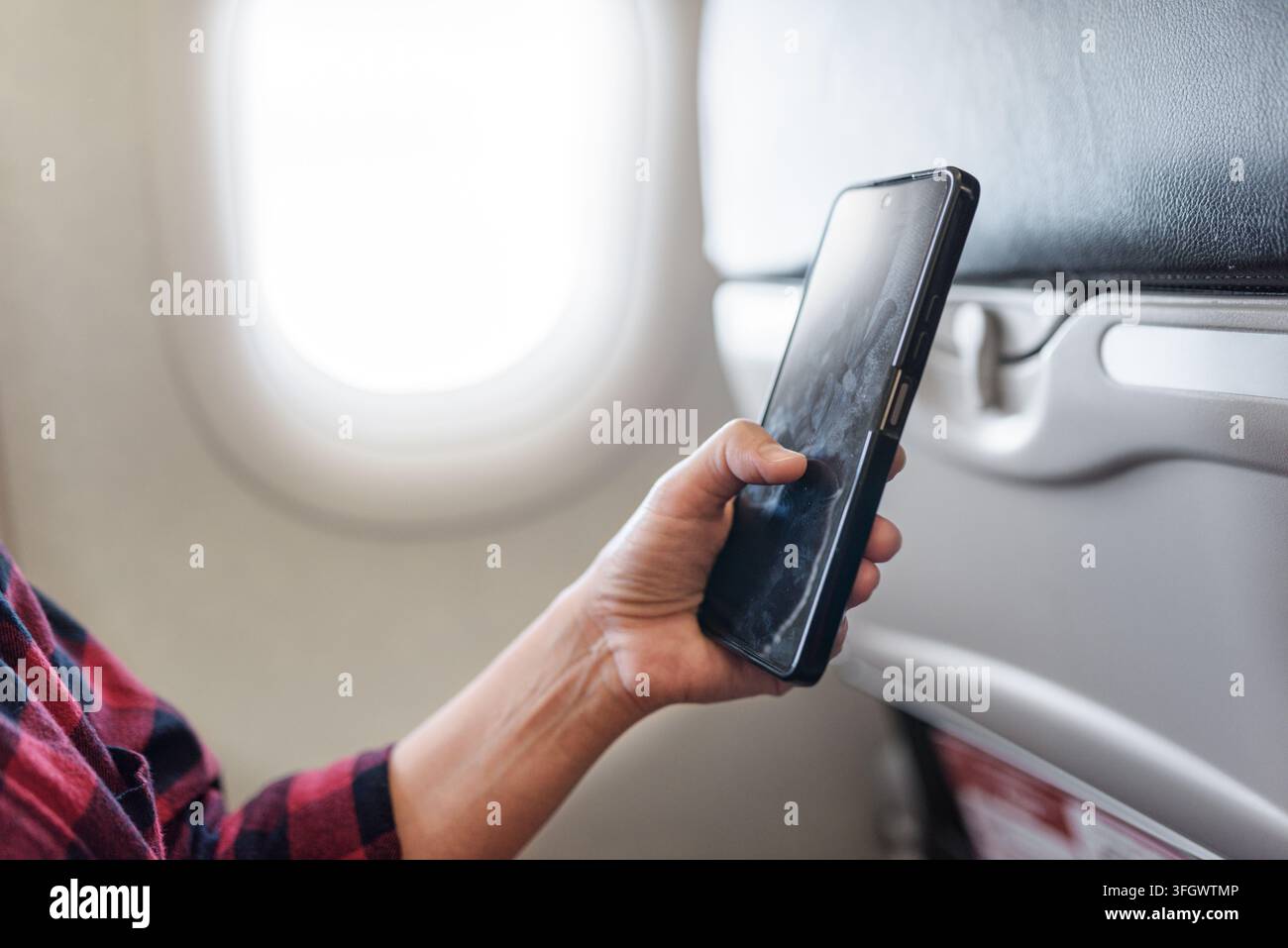 Nahaufnahme von Frauenhänden, die ein Smartphone in einem Flugzeug halten Stockfoto