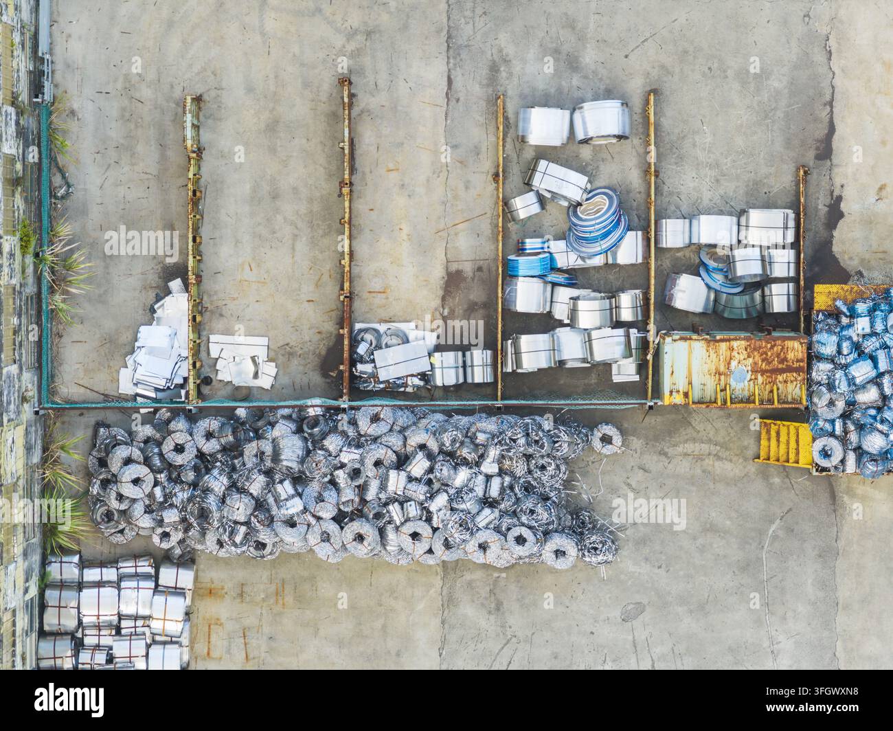 Luftaufnahme von Stapeln aus Schrottmetallspulen und Industrieabfall, die auf einem Betonhof in Taiwan gelagert sind. Stockfoto