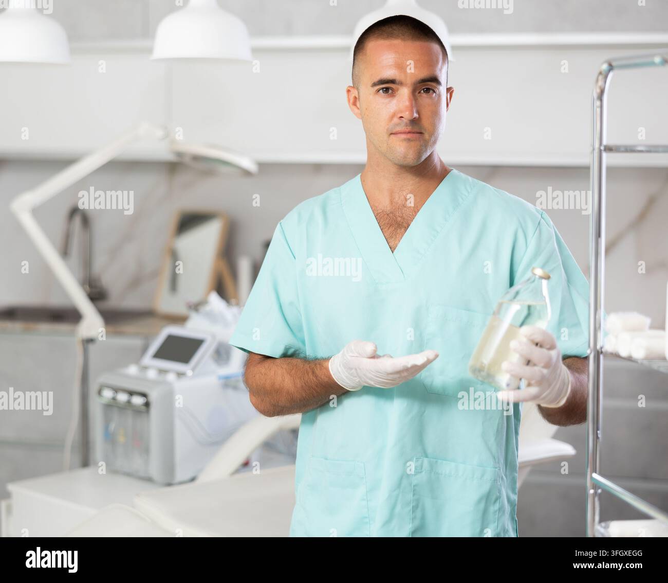Arzt steht neben dem Kosmetiktablett und zeigt Behandlungsstoffe vor dem Kosmetikschreibtisch Stockfoto