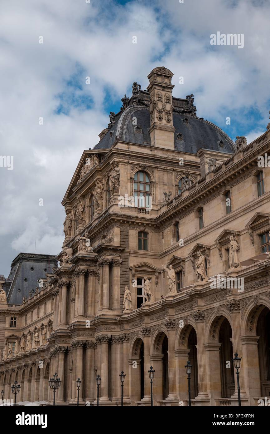 Historisches Louvre-Museum zeigt seine ikonische Pariser Architektur, aufwendige Skulpturen und klassisches Design unter einem dynamischen Himmel Stockfoto