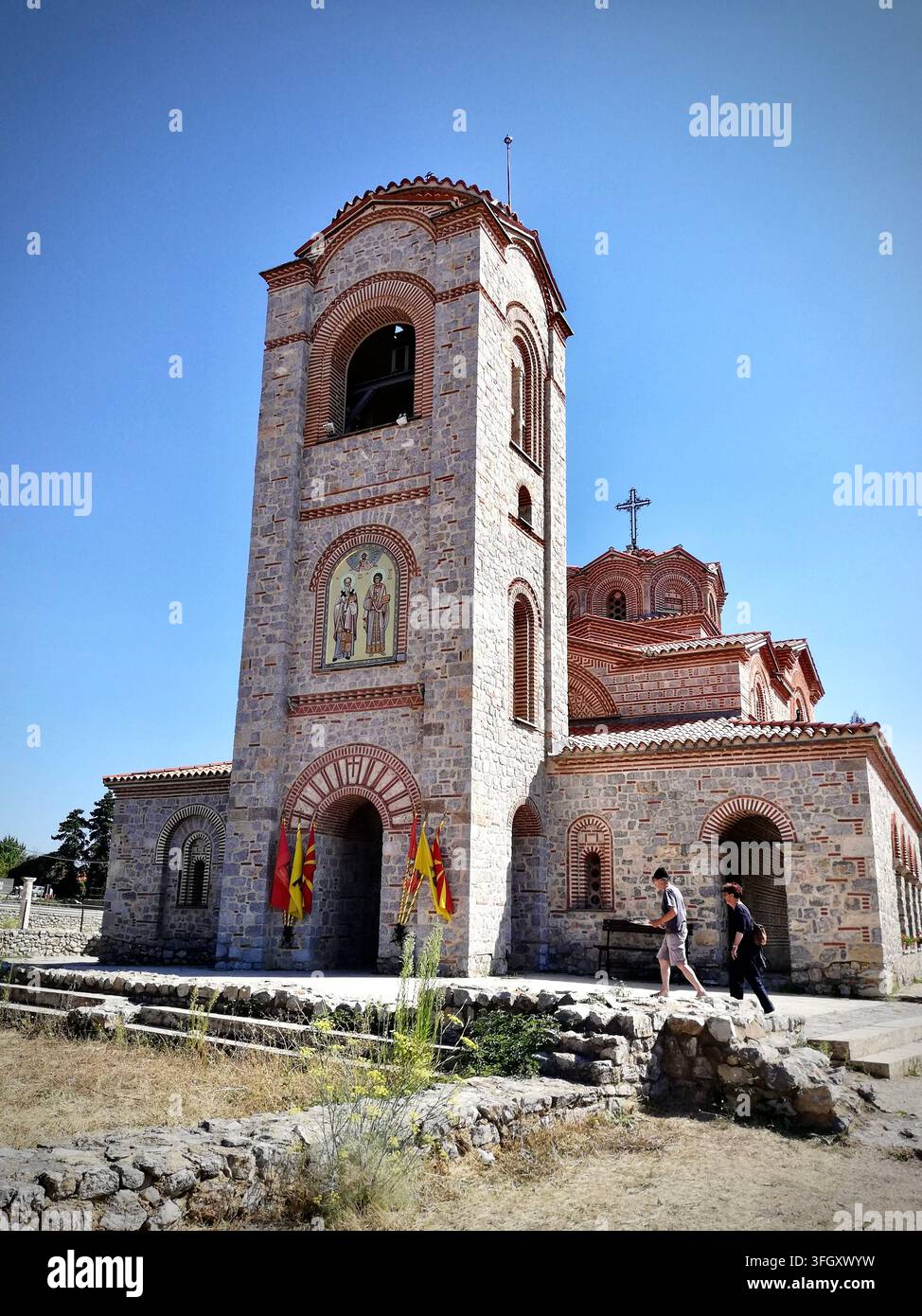 Byzantinische Kirche der Heiligen Clemens und Panteleimon in Ohrid, Nordmazedonien, mit einem steinernen Glockenturm und Freskomosaik unter einem klaren blauen Himmel. - Smartphone-aufgenommenes Stockfoto