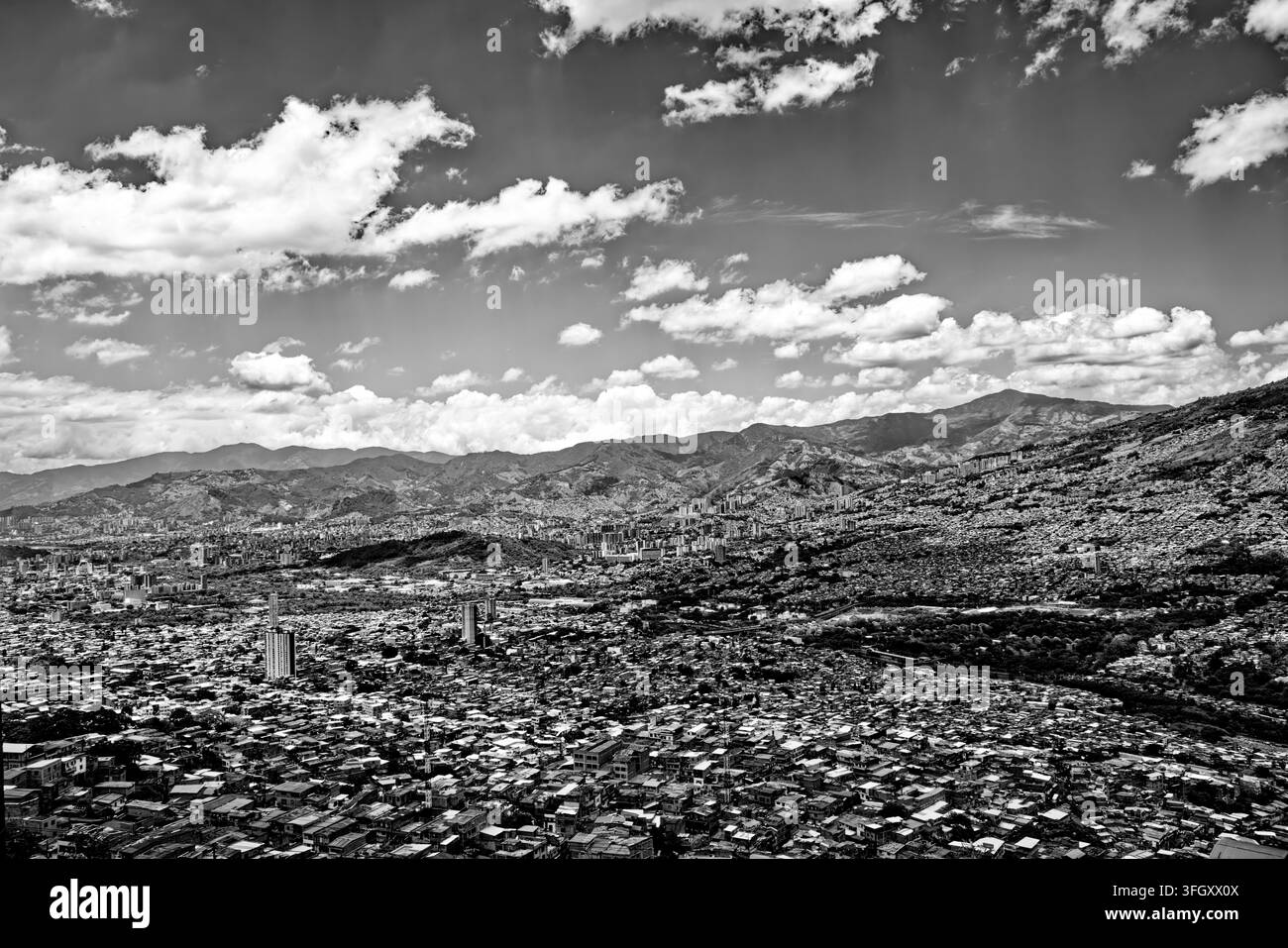 Dramatische Schwarz-Weiß-Luftaufnahme von Medellín, Kolumbien, die die dichte städtische Bebauung und die Ziegelhäuser zeigt, die sich die Hänge hinaufziehen. Stockfoto