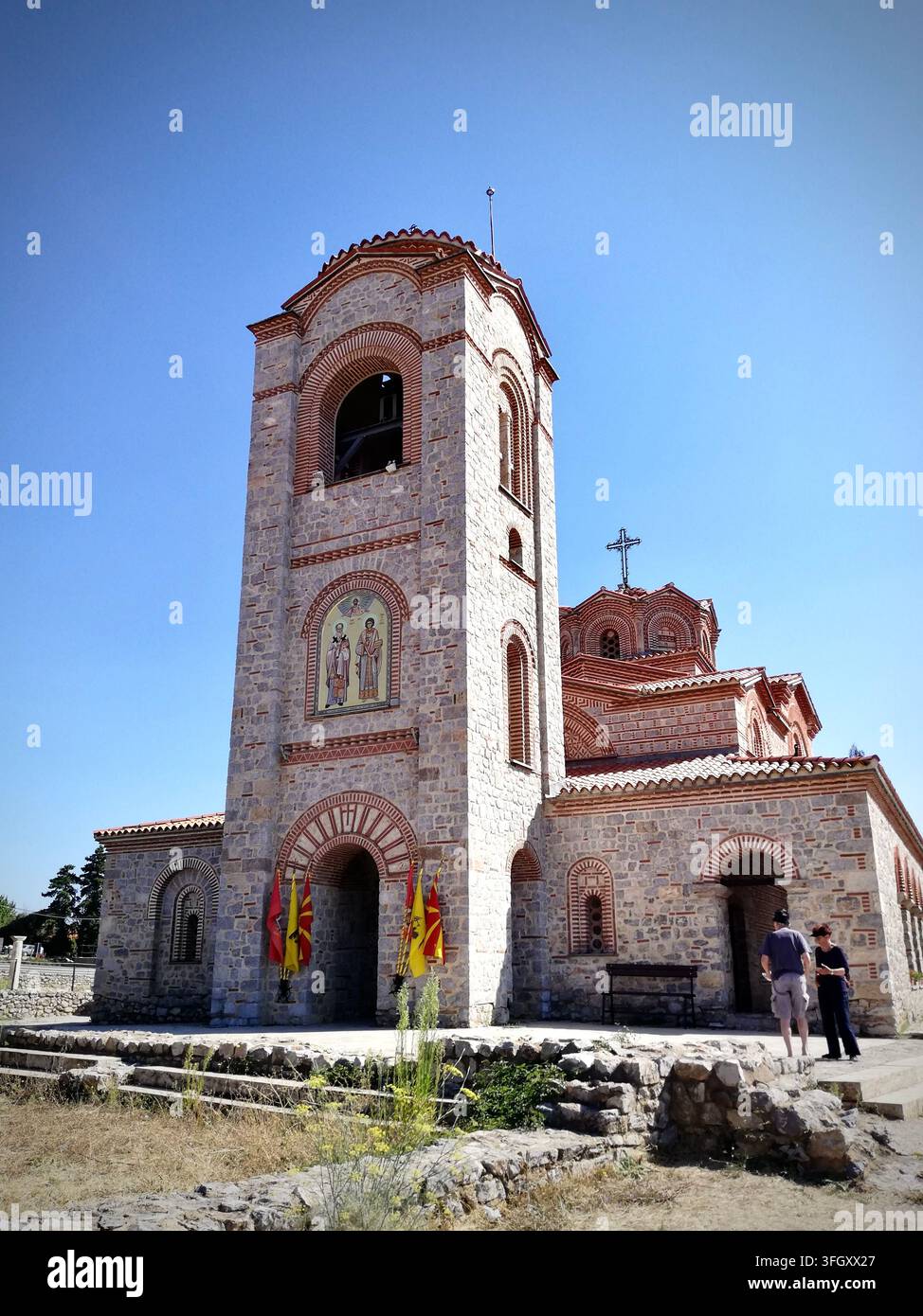 Byzantinische Kirche der Heiligen Clemens und Panteleimon in Ohrid, Nordmazedonien, mit einem steinernen Glockenturm und Freskomosaik unter einem klaren blauen Himmel. - Smartphone-aufgenommenes Stockfoto