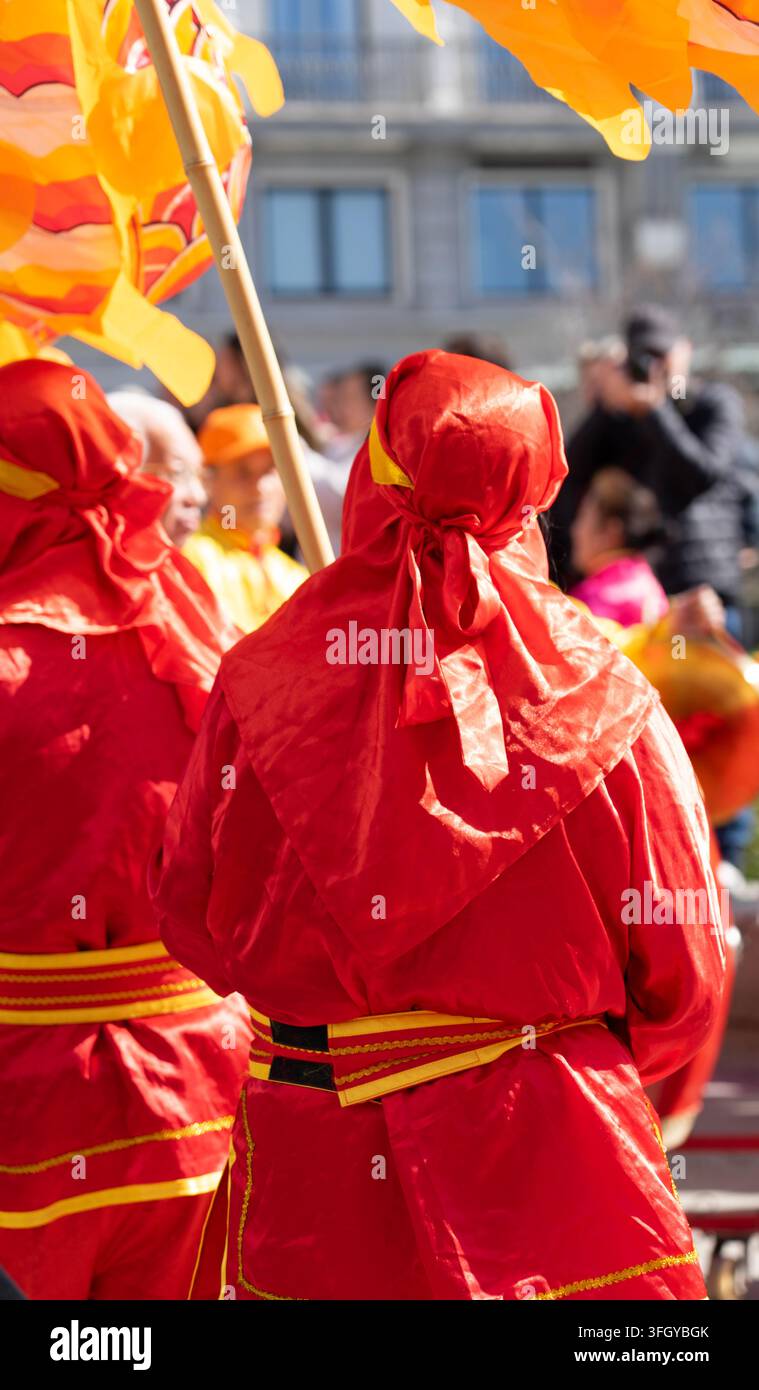 Eine Gruppe von Tänzern marschiert in roten Kostümen mit gelben Details, während sie einen chinesischen Drachen während der Frühlingsfest-Feier halten. Stockfoto