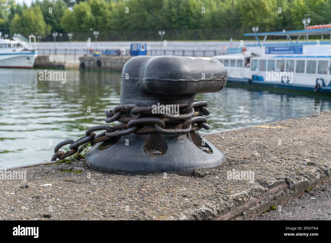 Schwarzer Ankerpfahl aus Gusseisen mit Kette am Pier Stockfoto