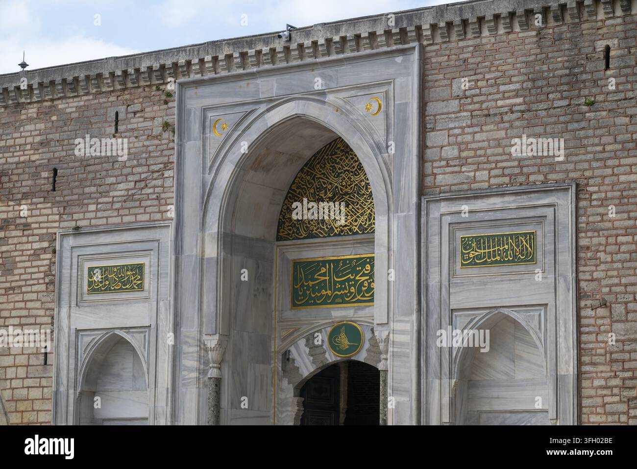 Ansicht des kunstvoll verzierten marmornen Imperialen Tores des Topkapi-Palastes mit aufwendiger Kalligraphie, goldenen Inschriften und Ziegelmauerwänden in Istanbul, I Stockfoto