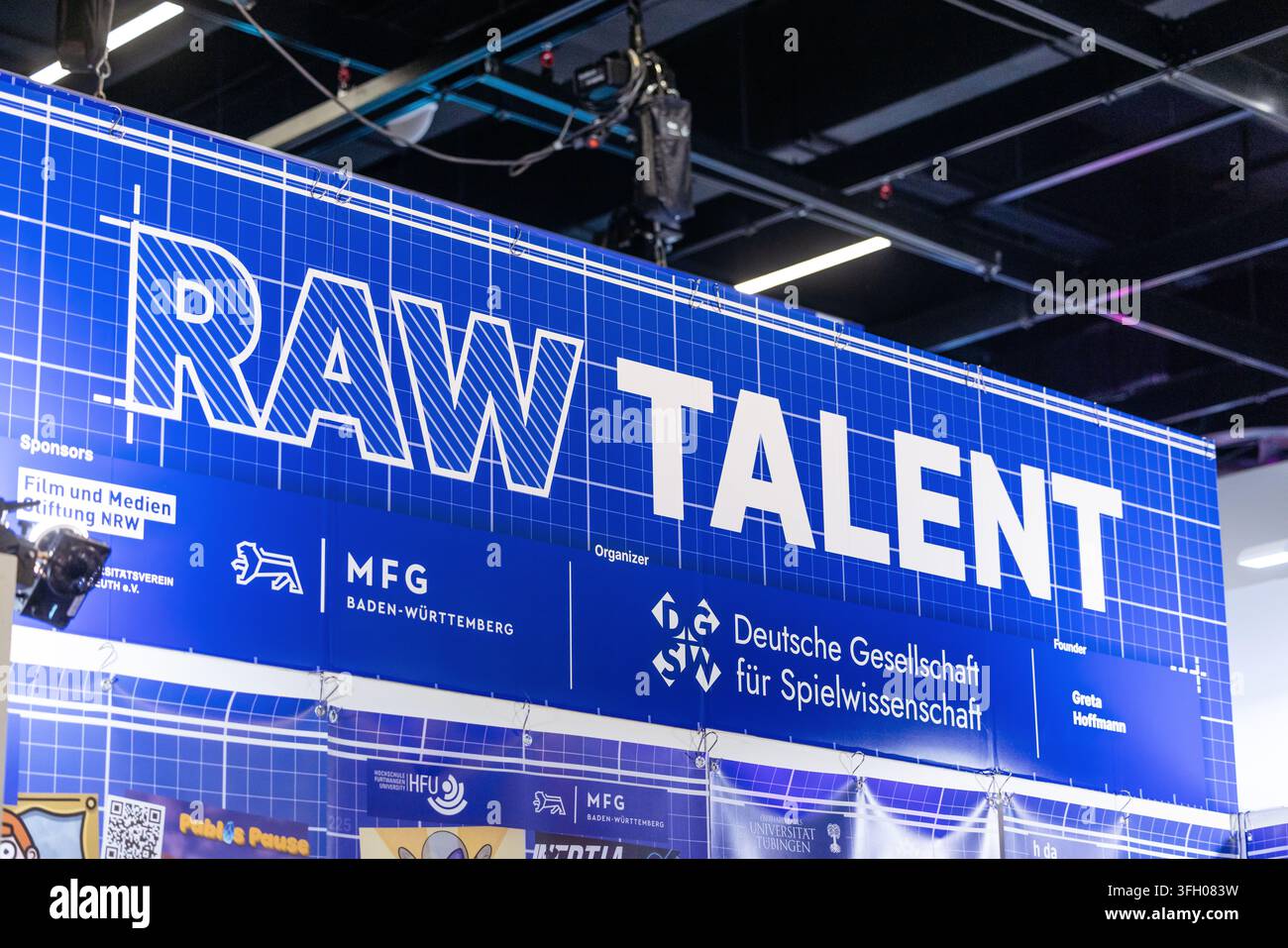 Köln, Deutschland – 26. August 2026: Blaues Banner mit der Aufschrift „RAW TALENT“ und Sponsorenlogos, das auf der gamescom ausgestellt ist, zeigt die Event-Branding und -Beförderung Stockfoto