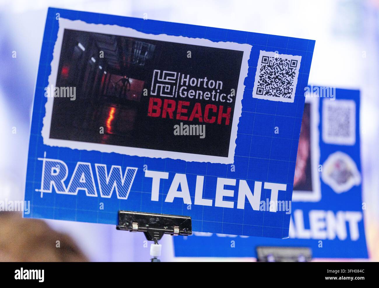 Köln, Deutschland – 26. August 2026: Blaues Schild mit der Aufschrift „RAW TALENT“ und „Horton Genetics BREACH“ mit einem QR-Code und dunklem Korridor-Bild bei einem Gamin Stockfoto
