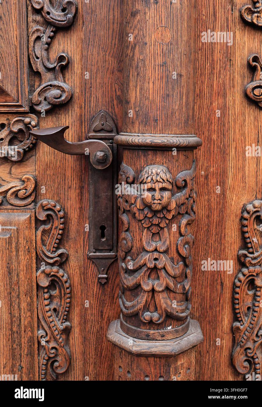 Tallinn, Estland – Nahaufnahme einer kunstvoll geschnitzten Holztür mit Puttenfigur-Relief, antiker Griff und Schlüsselloch Stockfoto