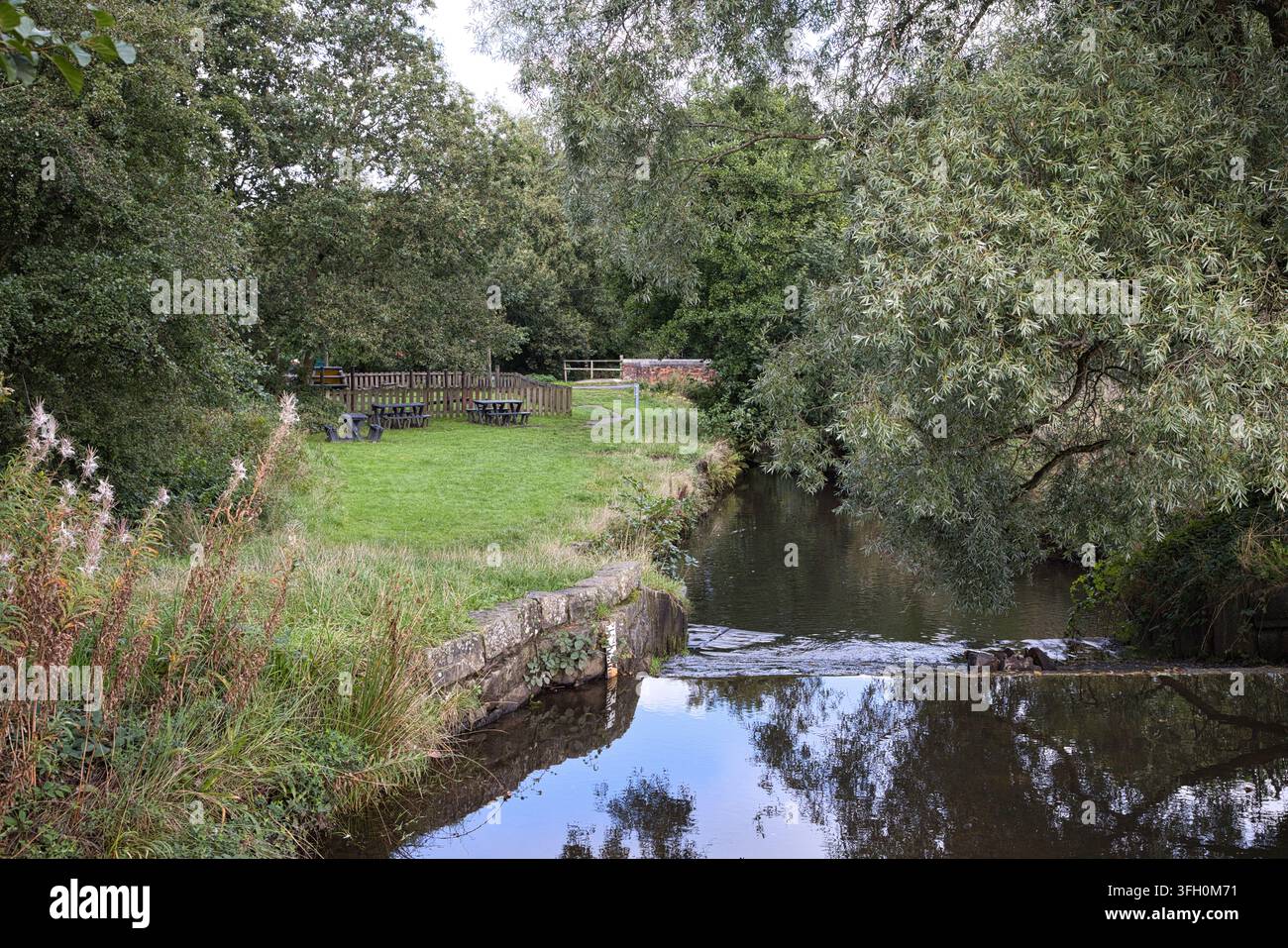Longden End Brook fließt durch eine malerische, von Bäumen gesäumte Landschaft mit Picknickbänken in der Nähe des Hollingworth Lake, Rochdale, UK. Stockfoto