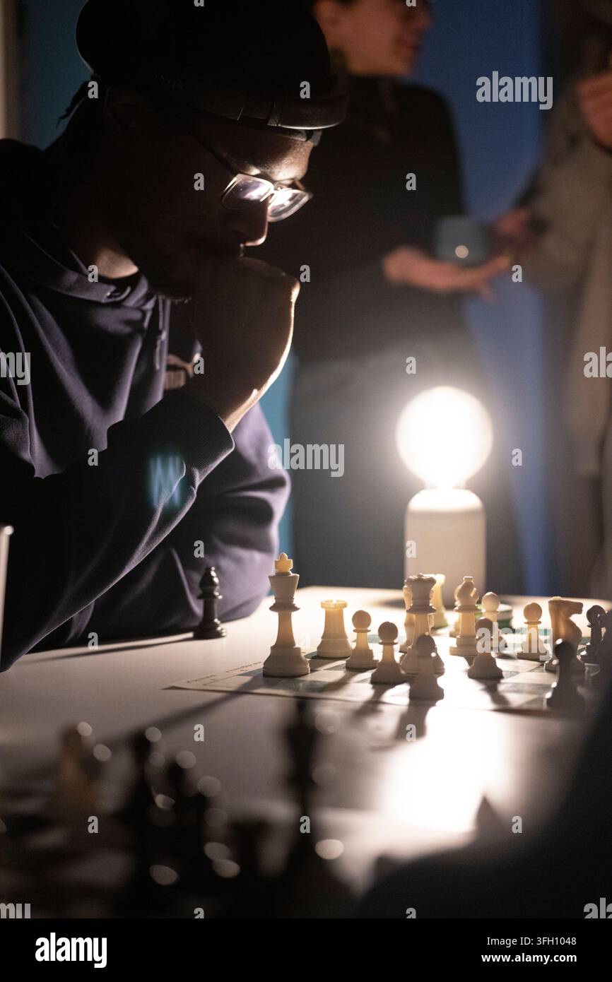 Ein konzentrierter Spieler überlegt intensiv seinen nächsten Zug, um ein Schachspiel unter warmem Licht zu strategisieren. Stockfoto