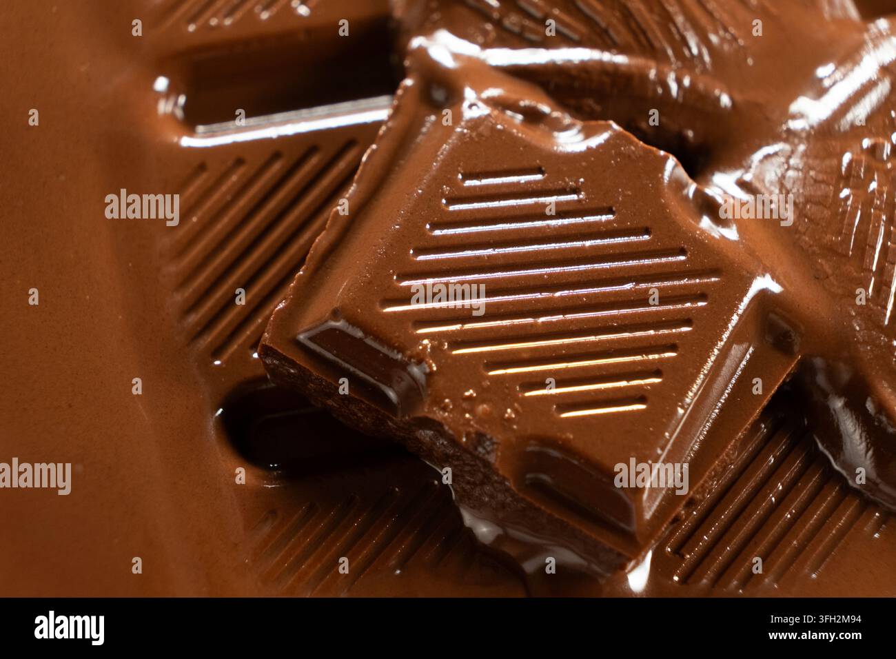 Weiche Schokoladenstückchen, die sich in einem warmen Pool aus flüssiger Schokolade auflösen. Stockfoto