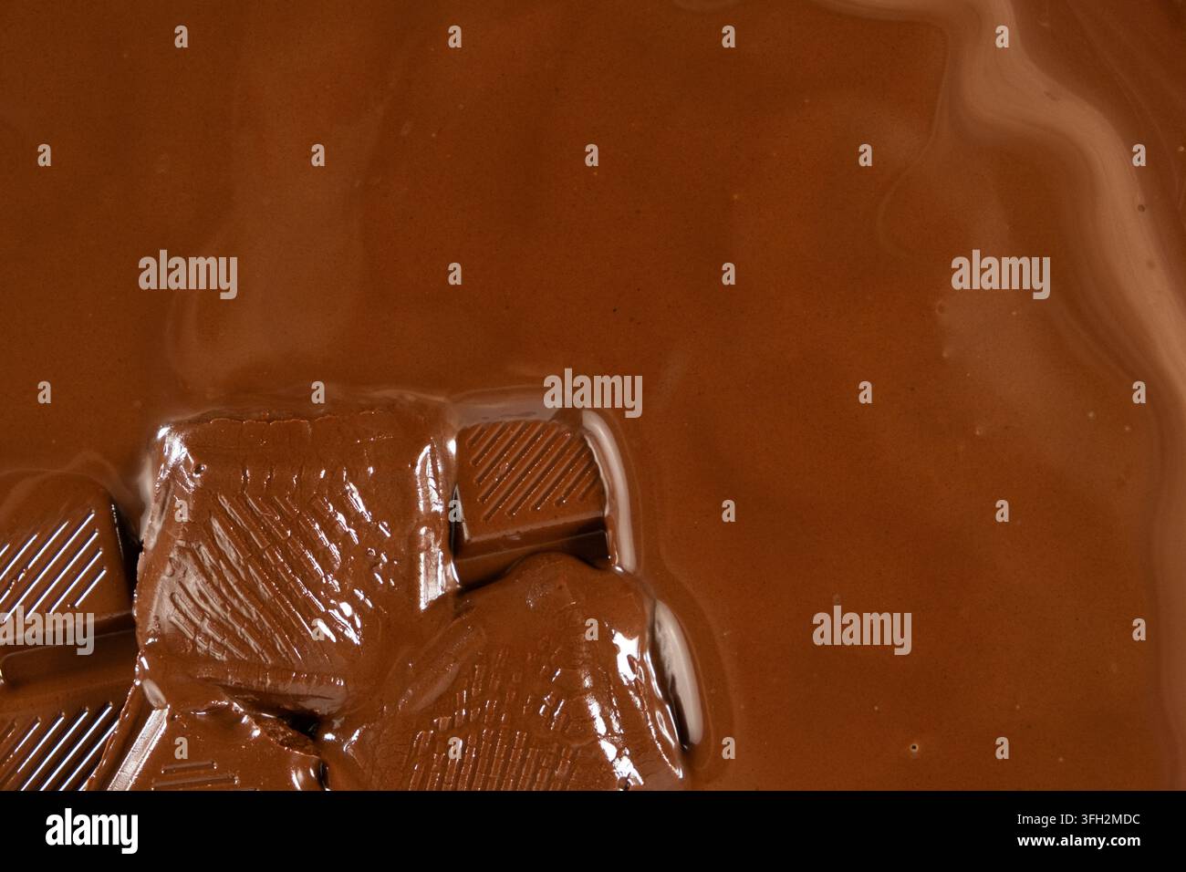 Schmelzende Schokoladenstücke in geschmolzener Schokolade, Nahaufnahme. Stockfoto