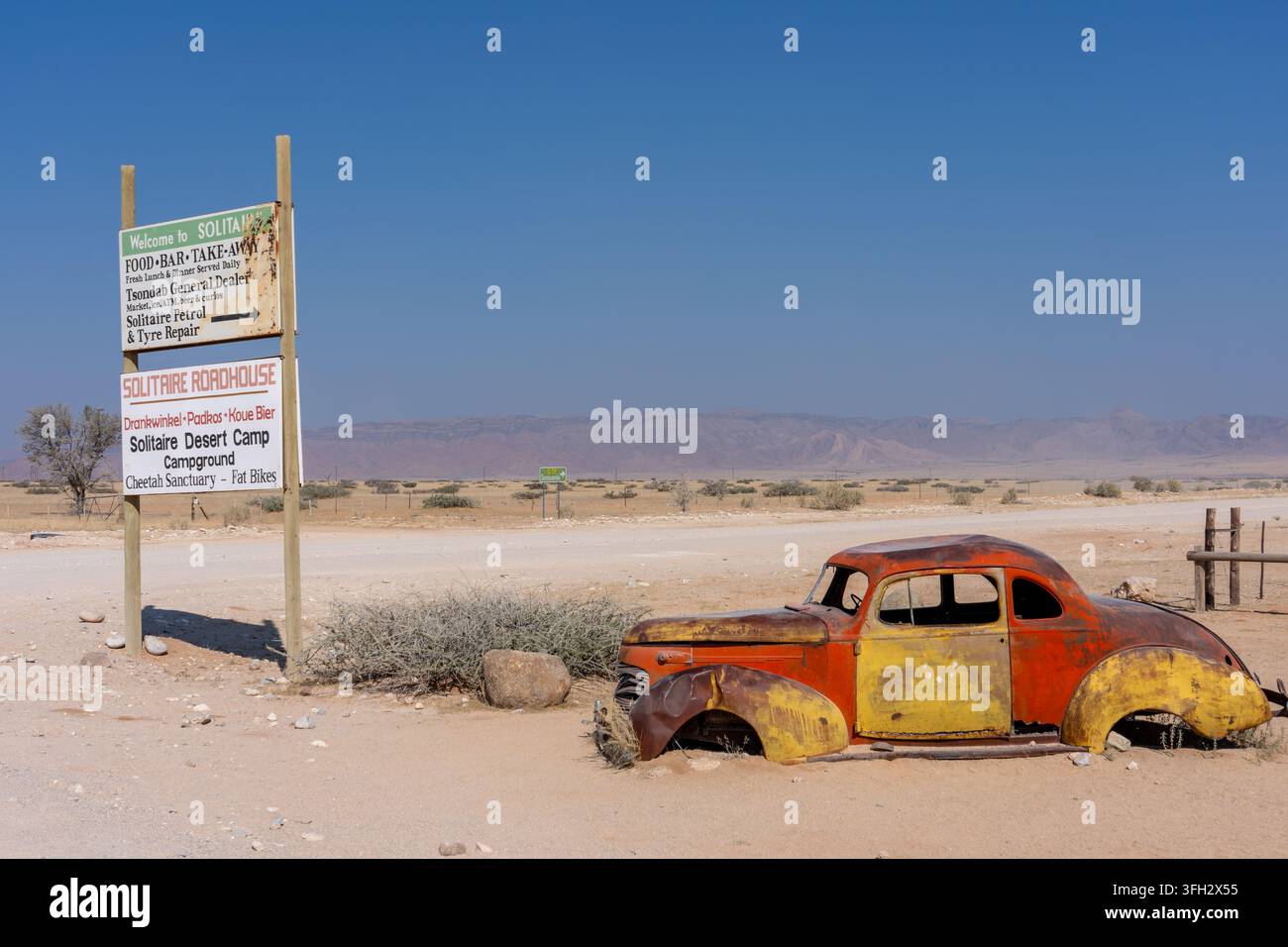 Straßenschild für Solitaire-Services neben einem verlassenen Oldtimer in der ländlichen Wüstenlandschaft der Kunene-Region, Namibia. Stockfoto