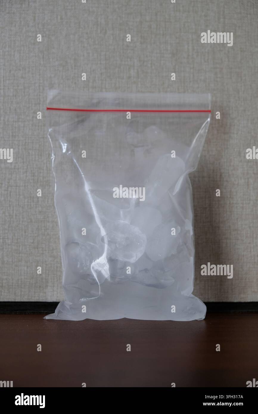 Klarer Plastik-Reißverschlussbeutel gefüllt mit Eiswürfeln auf neutralem Hintergrund Stockfoto