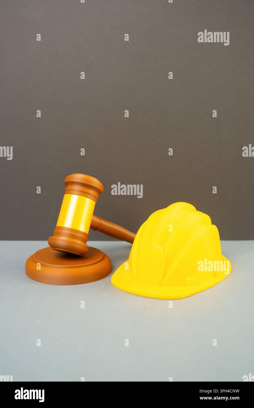 Ein gelber Sicherheitshelm und ein Richterhammer. Regelung von Bau- und Renovierungsgenehmigungen. Konzept der rechtlichen Konformität in der Bauindustrie und Sicherheit Stockfoto
