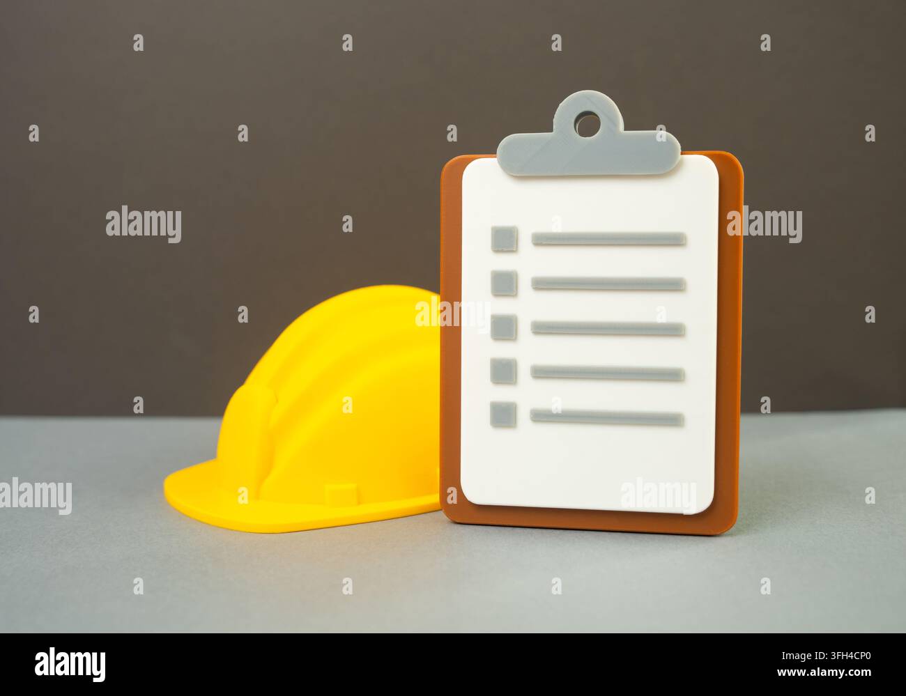 Ein gelber Sicherheitshut und ein Papier-Tablet. Sicherheitsinspektion. Konzept von Arbeitssicherheitsstandards und Qualitätskontrolle. Baustellenkontrollen und Audits Stockfoto