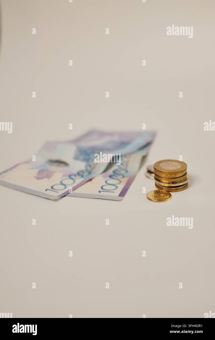 Kasachstanische Tenge-Banknoten und ein kleiner Stapel Münzen, angeordnet mit großzügigem Kopierraum, wodurch ein vielseitiges kommerzielles Bild für Ersparnisse, Budgetierung entsteht Stockfoto