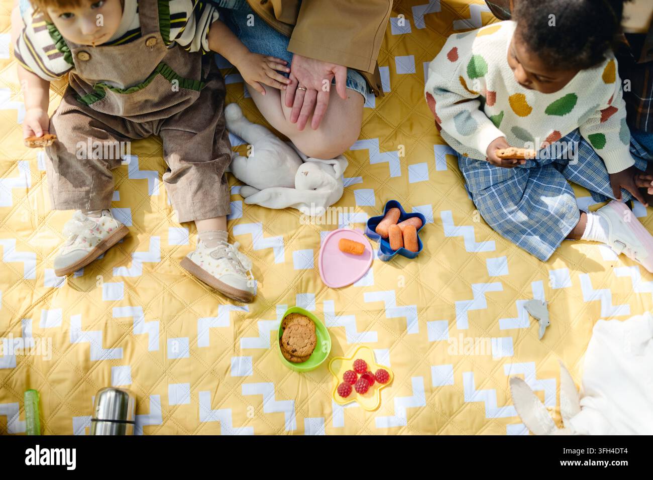 Multikulturelle Mütter und Kinder, die ein Picknick auf einer Decke im Park haben Stockfoto