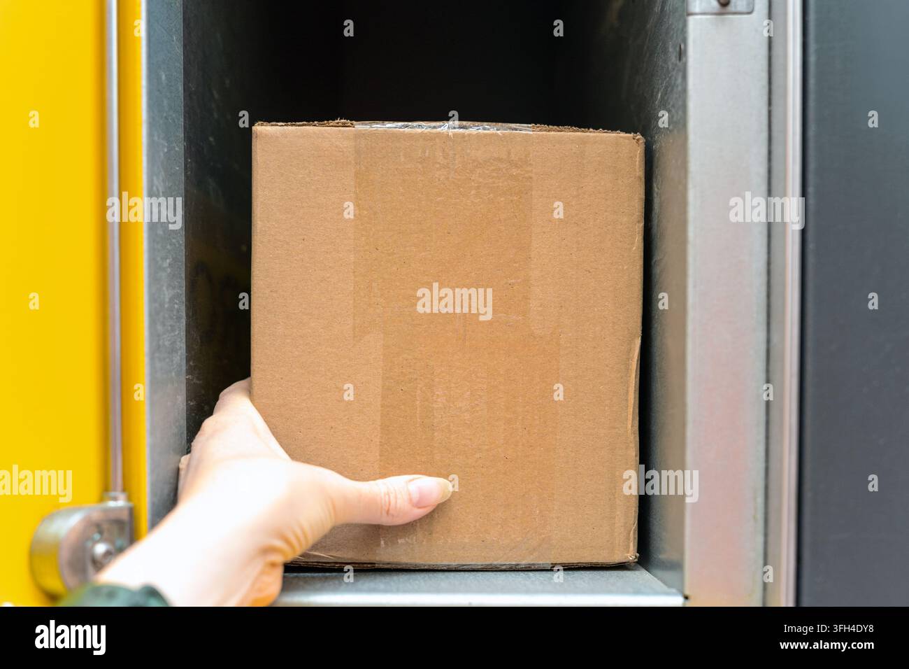 Kunde sammelt Kartonpaket aus automatisiertem Paketfach während der kontaktlosen Paketabholung Stockfoto