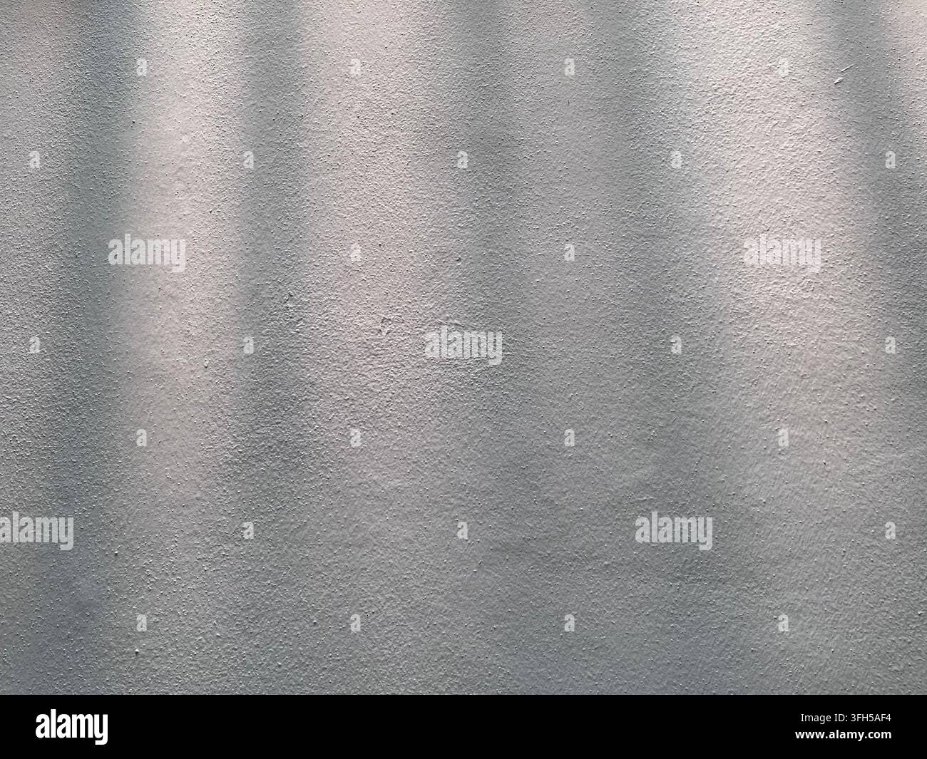 Abstrakte graue strukturierte Wand mit sanftem Licht und dezentem Schatten - Smartphone-aufgenommenes Stockfoto