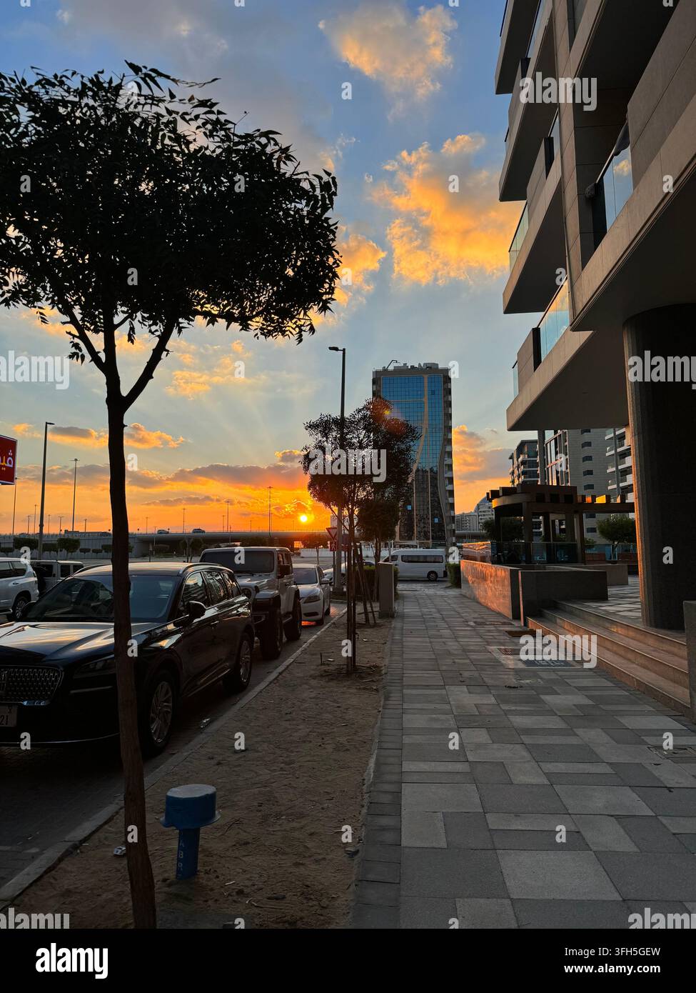 Stadtstraße von Abu Dhabi bei Sonnenuntergang mit modernen Gebäuden, Uferpromenade und warmem Abendlicht in den Vereinigten Arabischen Emiraten - Smartphone-aufgenommenes Stockfoto