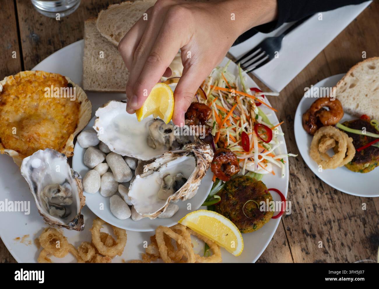 Köstliches Meeresfrüchtefest mit frischen Austern und herzhaften Beilagen in einem lebhaften Küsteneatery Stockfoto