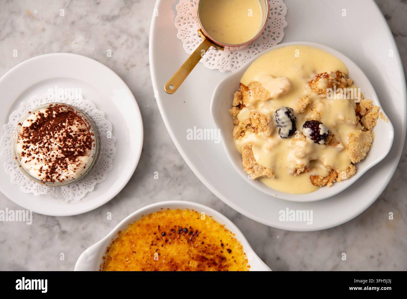 Köstliche Dessertaufstrich mit Sahne und süßen Köstlichkeiten auf einem Marmortisch Stockfoto