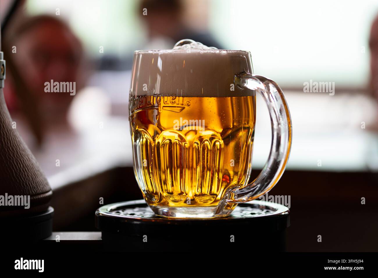 Erfrischendes goldenes Bier, serviert in einem gefrorenen Krug in einer lebhaften Kneipenatmosphäre Stockfoto