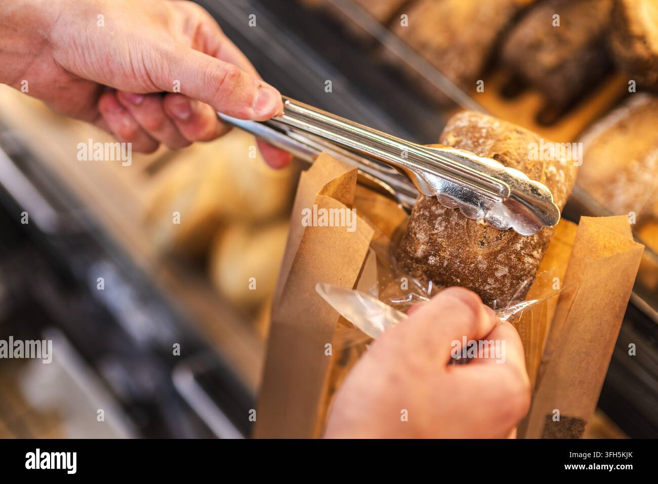 Hand wählt rustikales Brotlaib an der Bäckereiauslage aus Stockfoto
