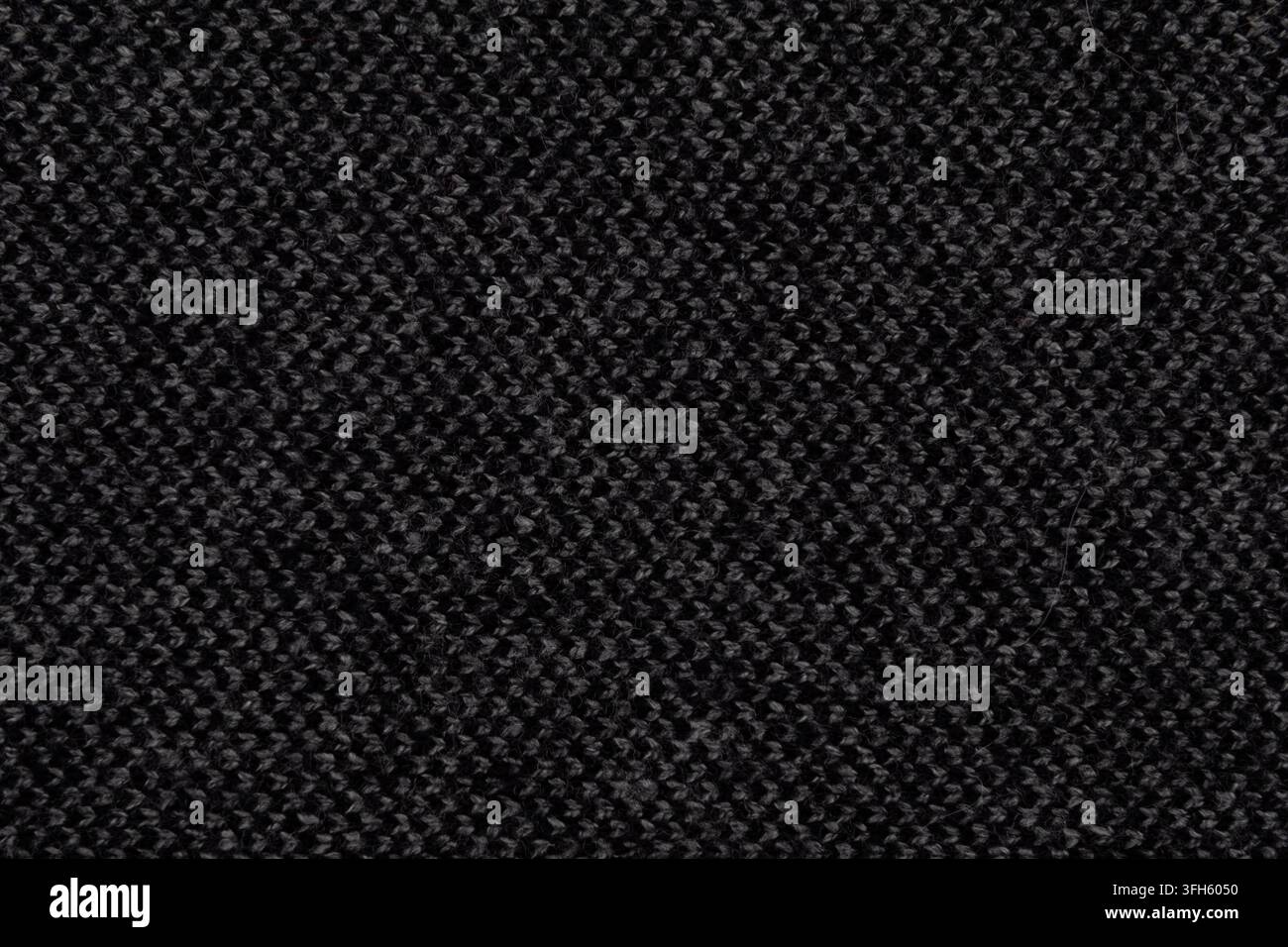 Makrotextur von dunkelgrauem Strickwollstoff mit dicht gewebtem Muster. Feiner Strickhintergrund mit subtilen Lichtreflexen Stockfoto