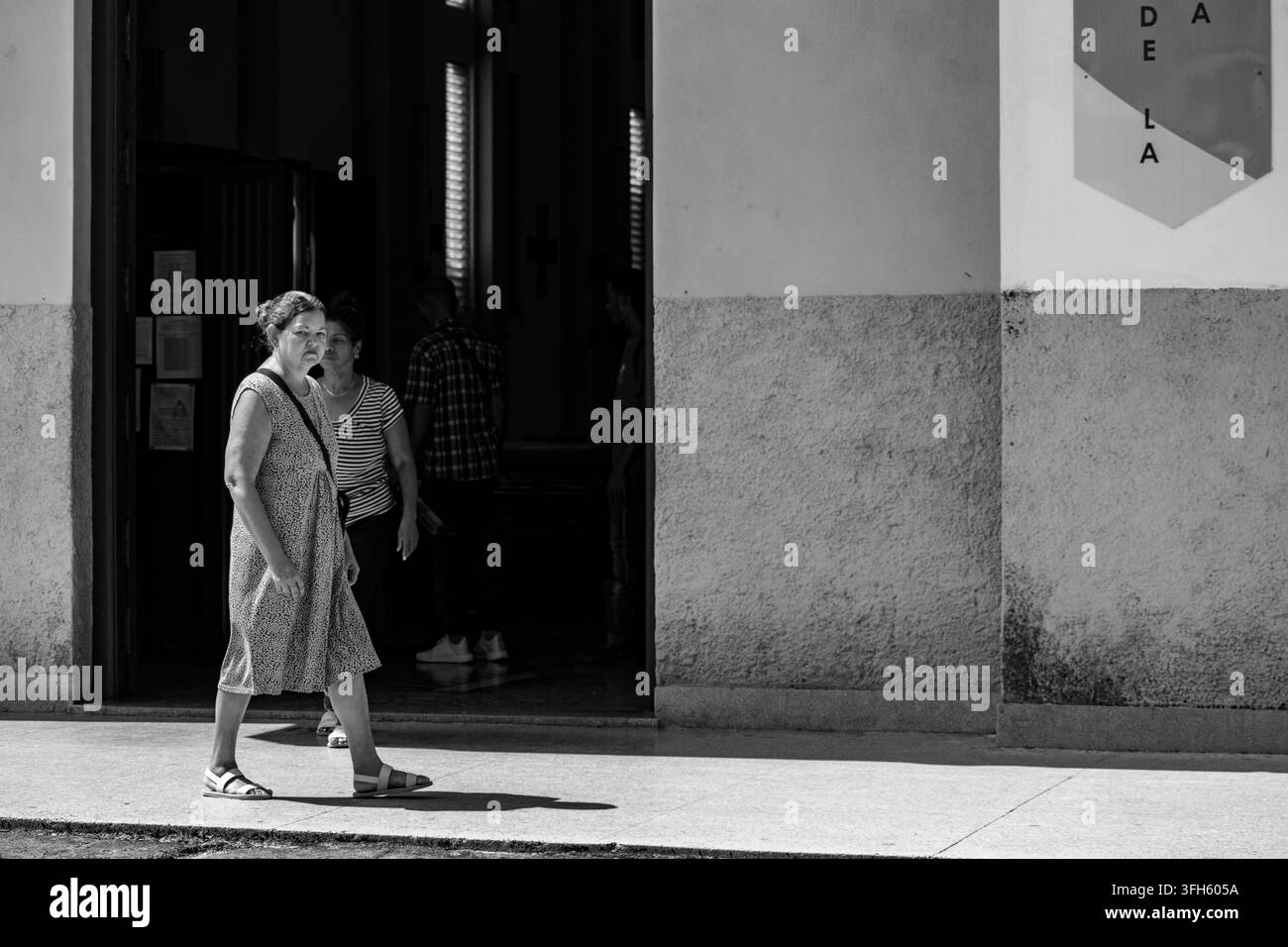 Schwarzweiß-Straßenfotografie einer Frau, die entlang der Independencia-Straße in Ciego de Avila, Kuba, geht - 21. August 2026 Stockfoto