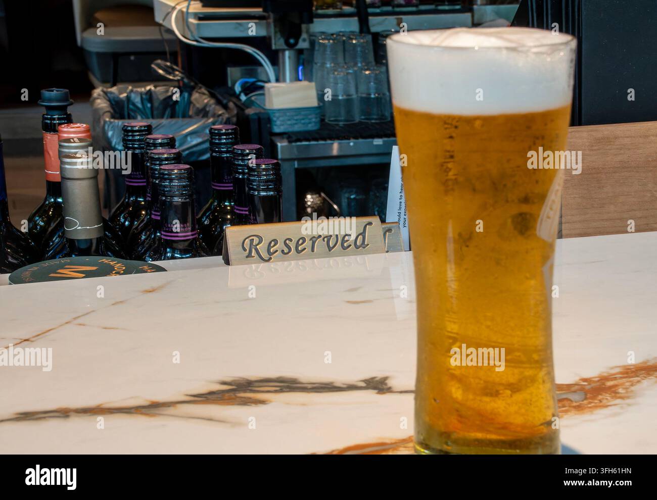 Ein hohes Glas helles goldenes Bier, gekrönt mit einem dicken weißen Schaumkopf an einem ruhigen Platz an der Bar. Stockfoto